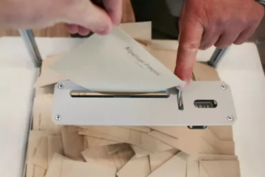 Personne qui tient son bulletin de vote au-dessus de l'urne