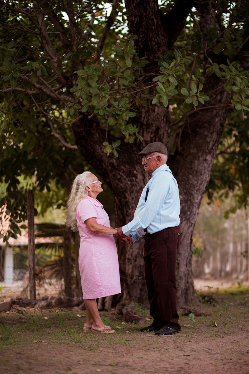 Une femme et un homme se tenant la main devant un arbre; fêtent l'anniversaire de mariage