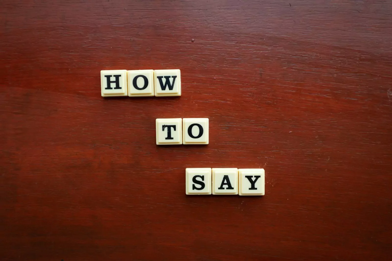 scrabble tiles spelling how to say on a wooden surface